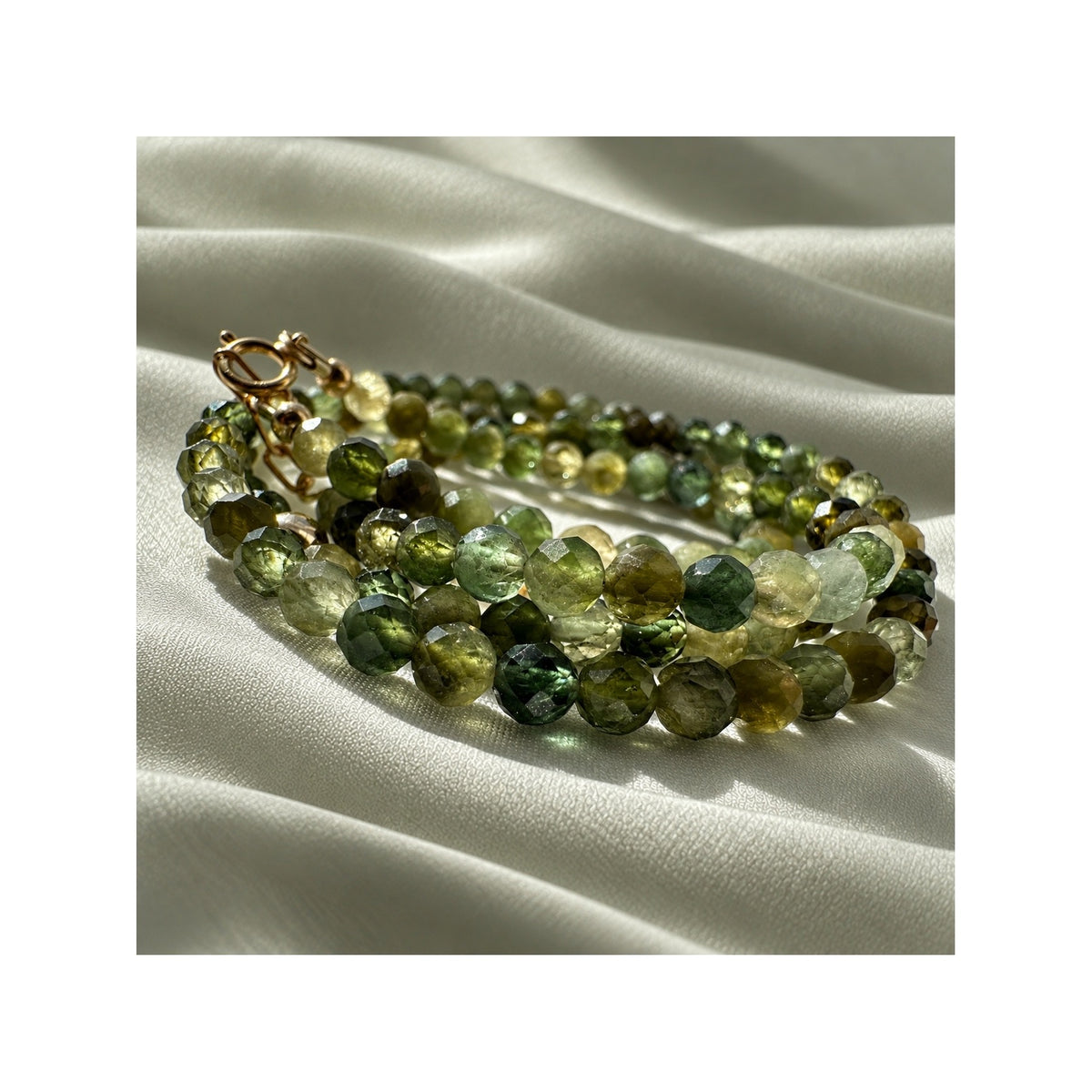 Close-up of natural faceted green tourmaline gemstones in the FOREST GREENS necklace