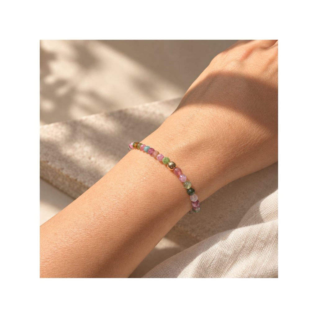 FLORA multicolour tourmaline stretch bracelet worn on wrist, with natural pink and green faceted gemstones and a single solid 14k gold bead