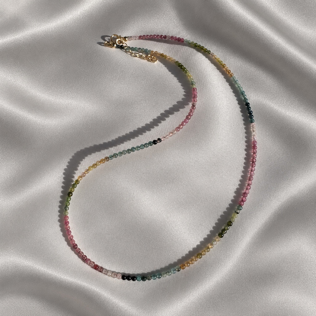 Full COLOUR POEM necklace showing its fine line of smooth 2 mm tourmaline beads and 14k gold-filled details on pearl-grey silk